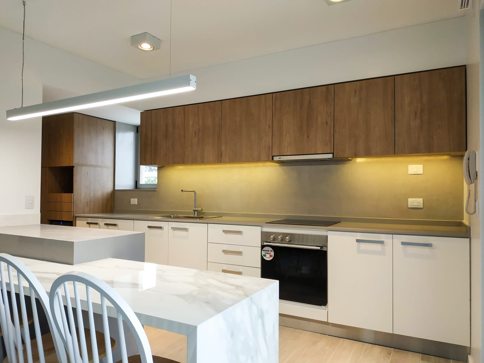 Cocina moderna con isla de mármol y frente de bronce